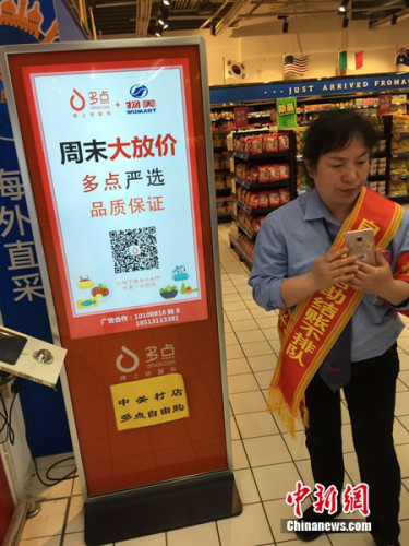 超市工作人员在给顾客讲解如何使用自助结账服务。中新网 吴涛 摄