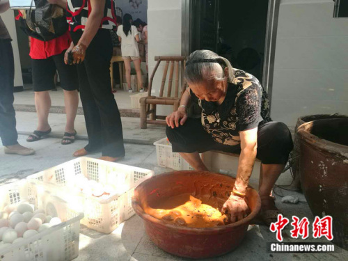 廖奶奶亲自为咸鸭蛋裹上黄泥。 中新网记者 张尼 摄