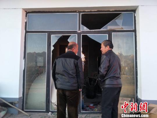 图为爆炸现场附近民众通过一间门窗及后墙被炸通的商铺向里张望。　乌娅娜 摄