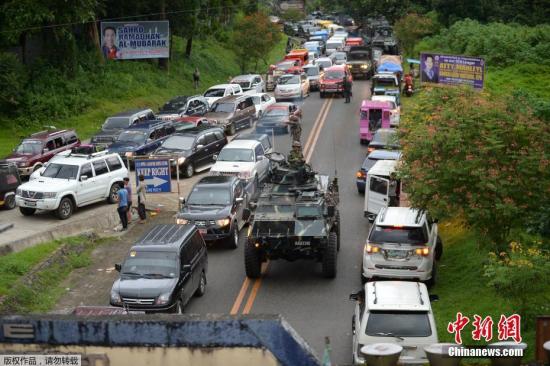 当地时间2017年5月25日，菲律宾马拉维市，当地民众驾车逃离马拉维市，道路严重拥堵，菲军方装甲车穿行其间。