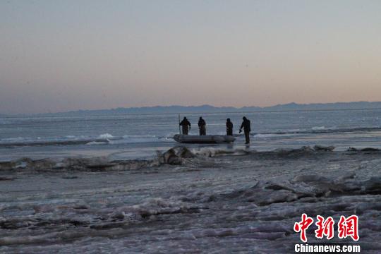 图为救援人员携带橡皮艇徒步进入青海湖。　胡贵龙 摄