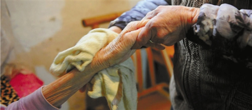 陈琳瑛帮婆婆用热毛巾擦手，她自己的手也已经满是皱纹。