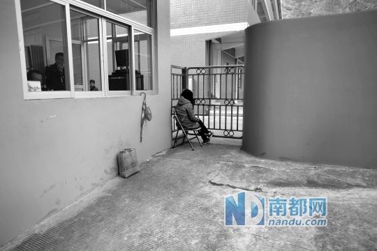 昨日，小潘拿着凳子坐在涉事企业门外，其家属在一旁讨要说法。南都记者 郭继江 摄