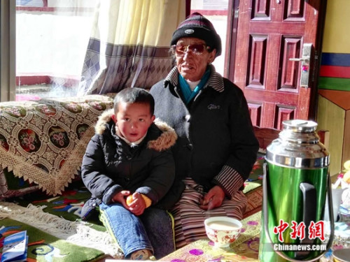 罗吉抱着孙子向记者讲述自己家的变化。中新网记者 宋宇晟 摄